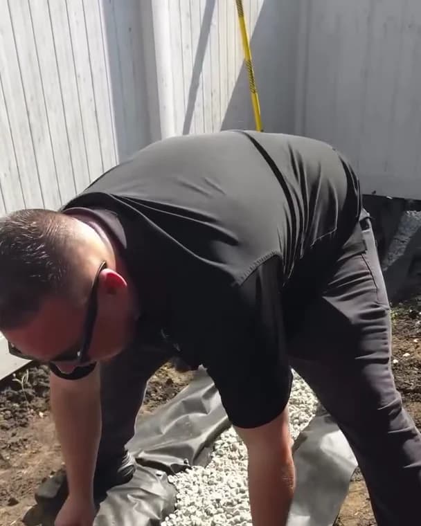 Contractor folding TERRA nonwoven fabric over the gravel to wrap a French drain