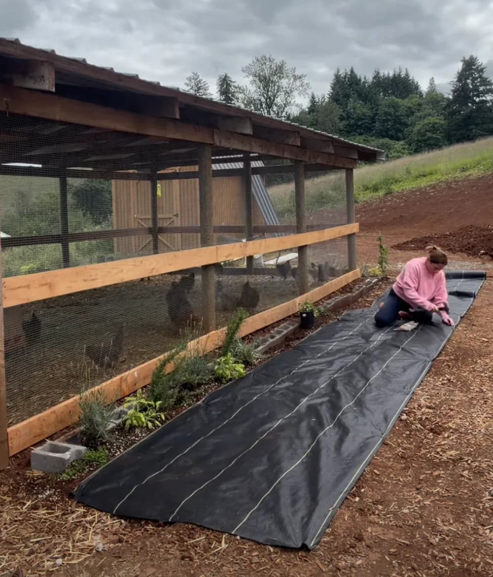 Briana laying DOTDAY XBAR 5oz woven fabric along her chicken coop and farm beds in Oregon