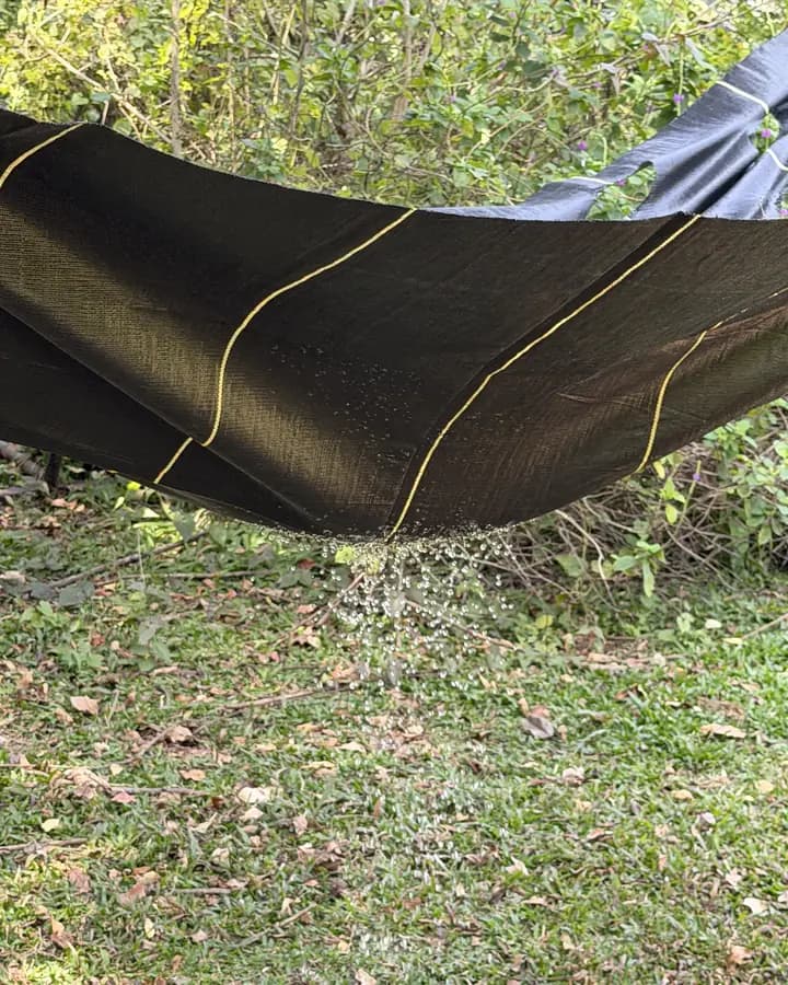 Water draining straight through DOTDAY woven landscape fabric held above the grass