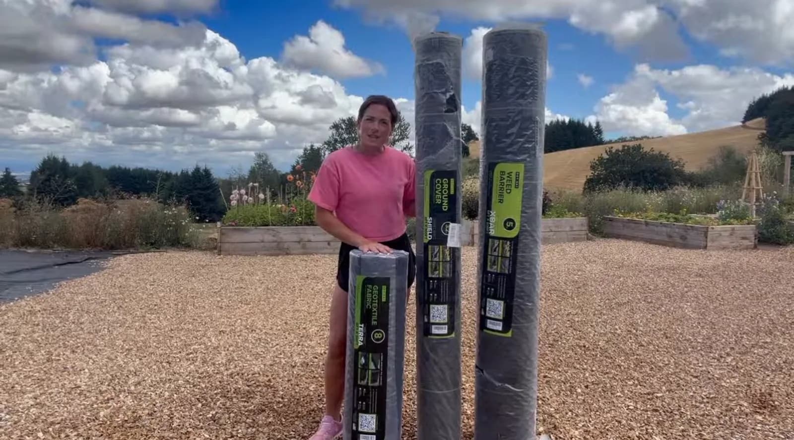 Grower holding DOTDAY TERRA, SHIELD, and XBAR rolls side by side, the three weights on the landscape fabric thickness chart