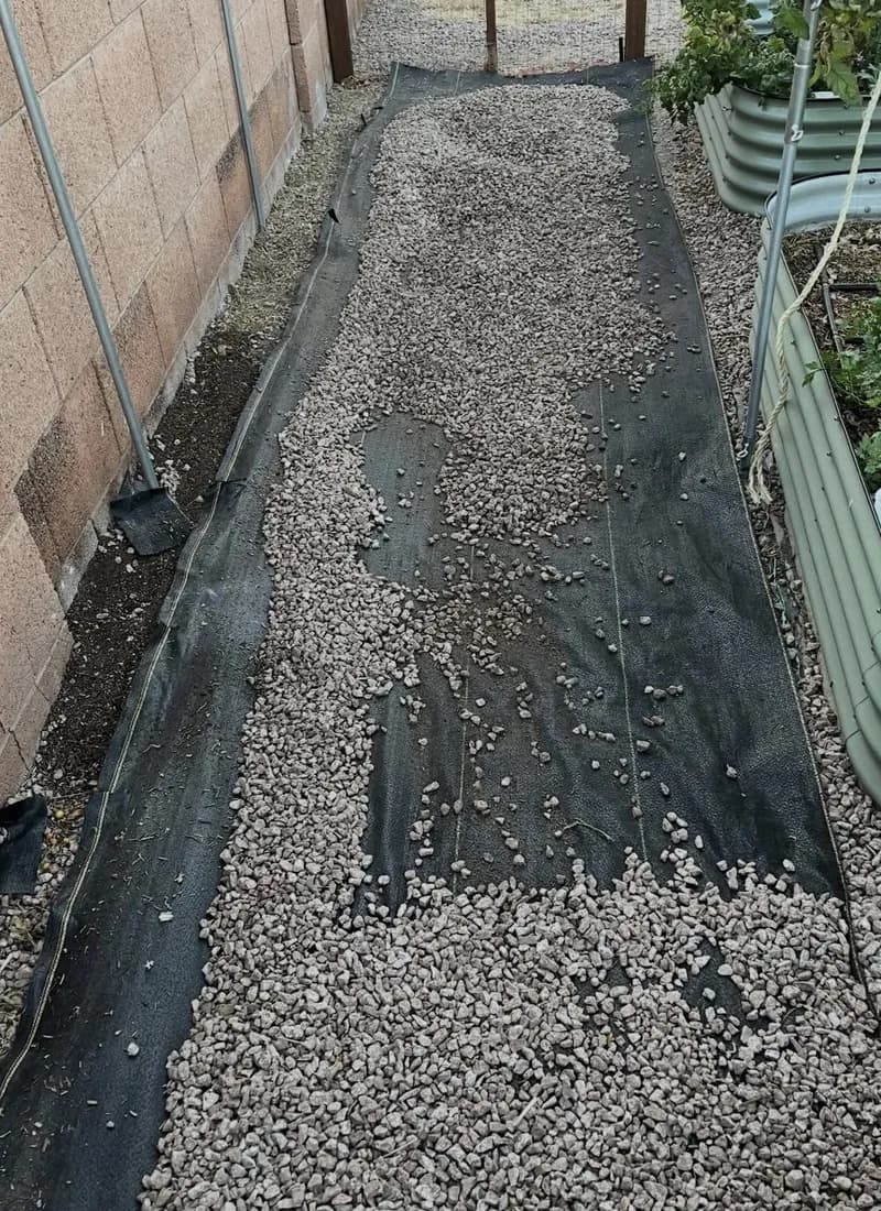 DOTDAY XBAR fabric laid under gravel along a side-yard path