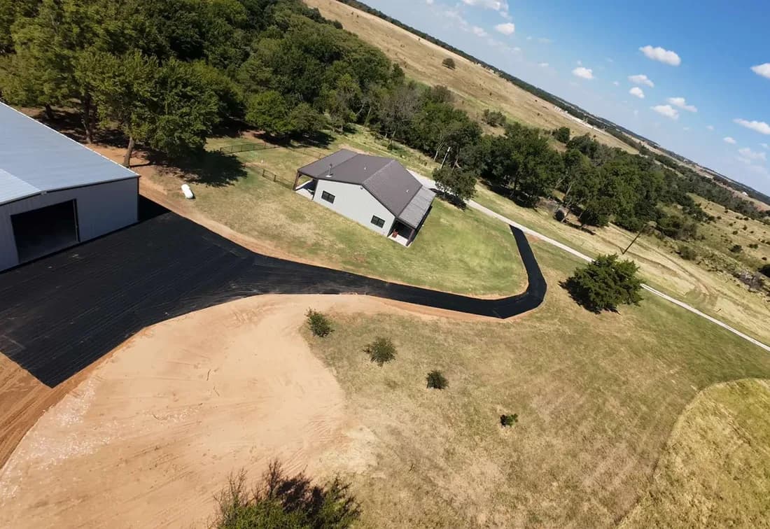 Geotextile fabric on a real job: DOTDAY XBAR 5oz dual-layer woven fabric laid across a driveway and shop pad before gravel, seen from above