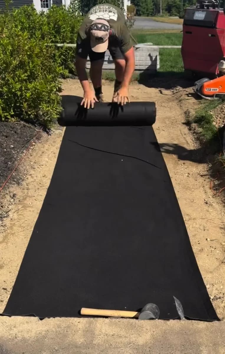 Contractor unrolling DOTDAY TERRA geotextile along a prepared path before gravel is added