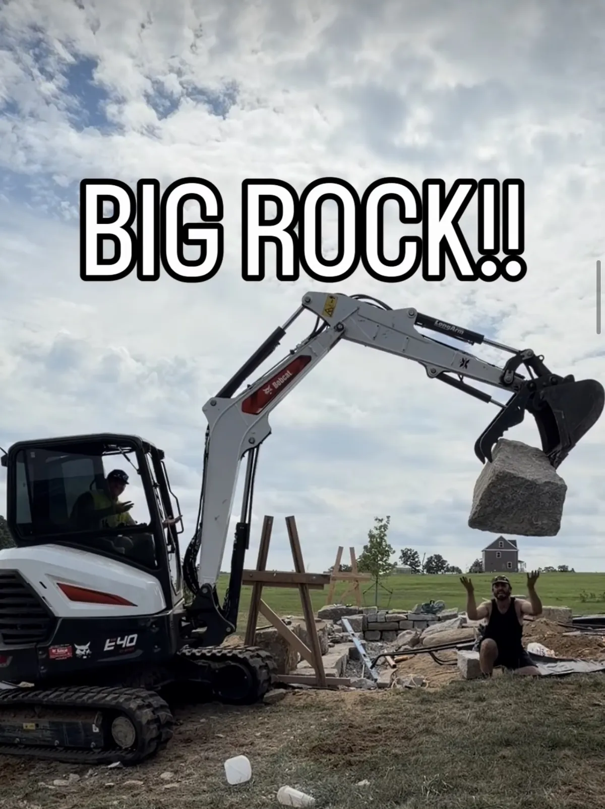 Bobcat E40 excavator swinging a granite boulder on a wall build
