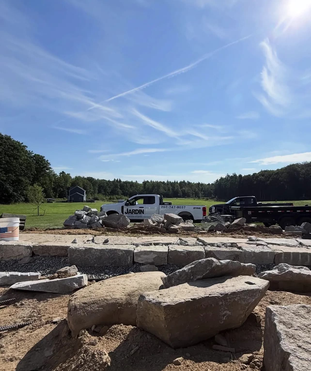 Granite blocks staged over a crushed stone base with work trucks on site