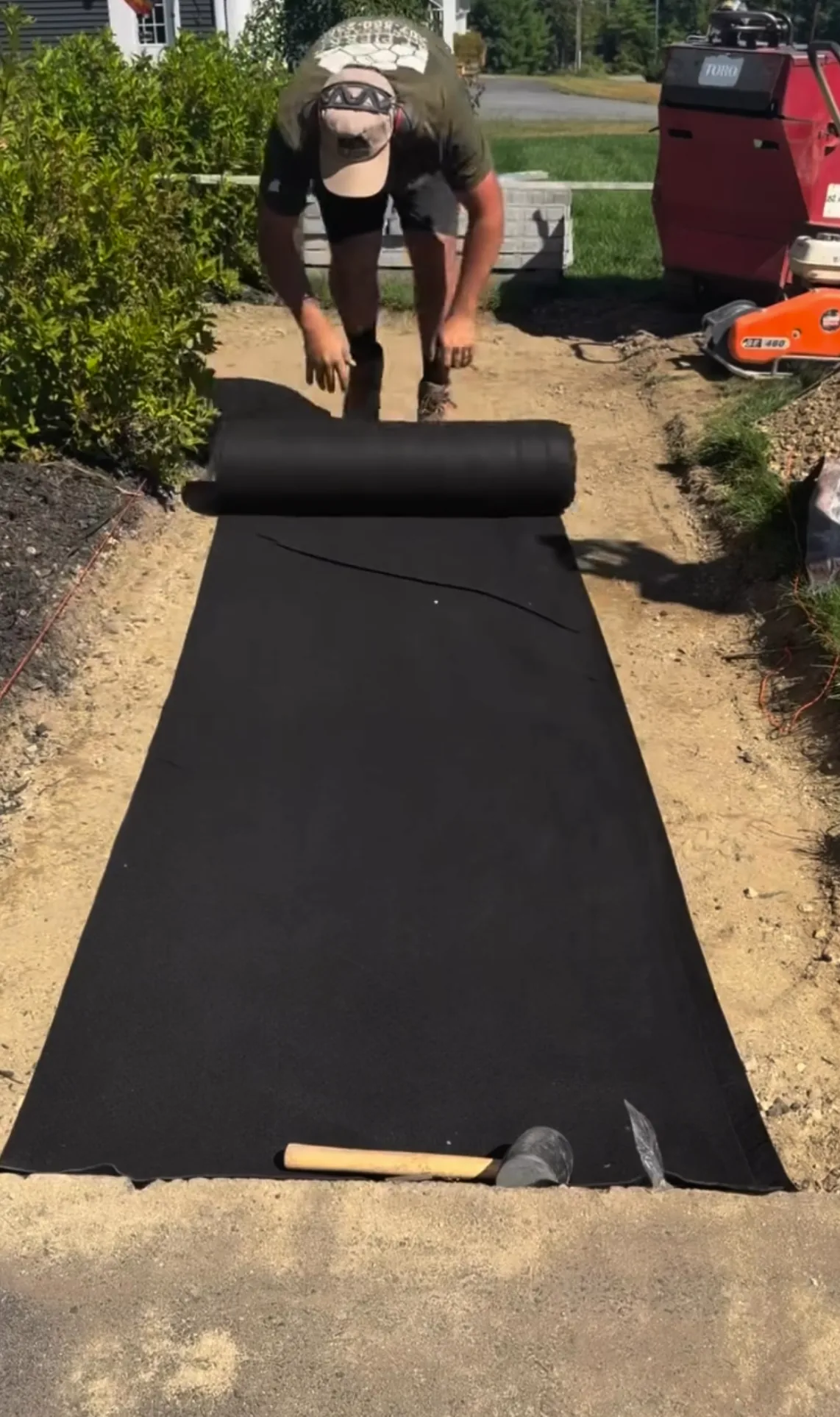 Jeff rolling DOTDAY TERRA fabric across the graded walkway subgrade