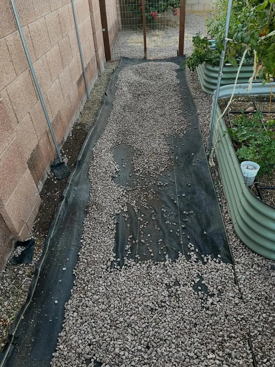 SHIELD woven fabric laid along a garden path beside raised beds