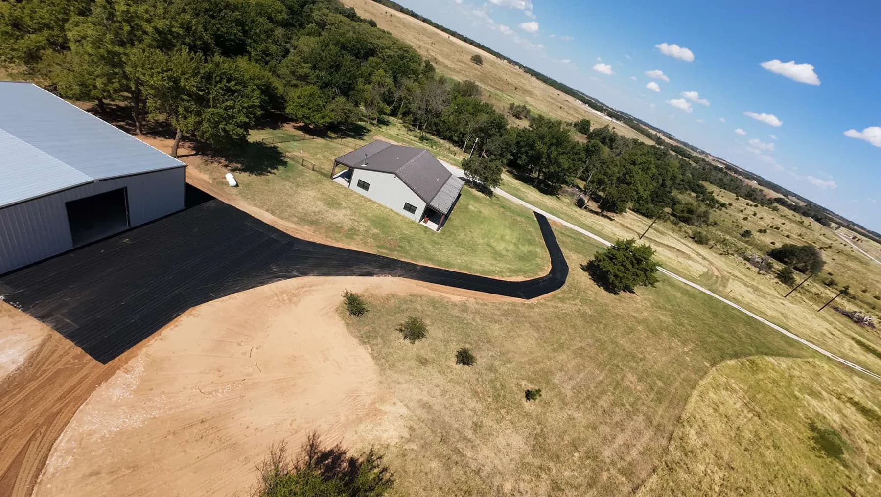 Drone view of black XBAR fabric covering the shop pad and driveway before gravel