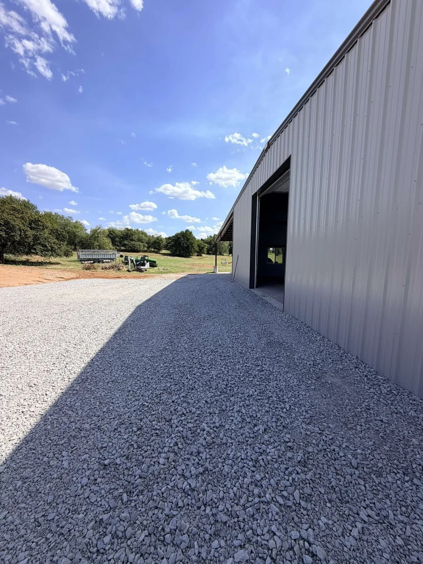 Finished compacted crushed rock shop pad at the open bay door after the gravel went over the XBAR fabric
