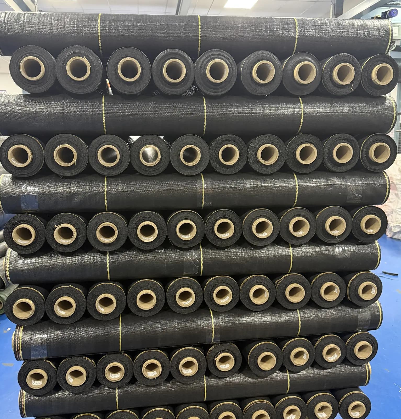 Finished woven landscape fabric rolls stacked on a pallet at our manufacturing facility